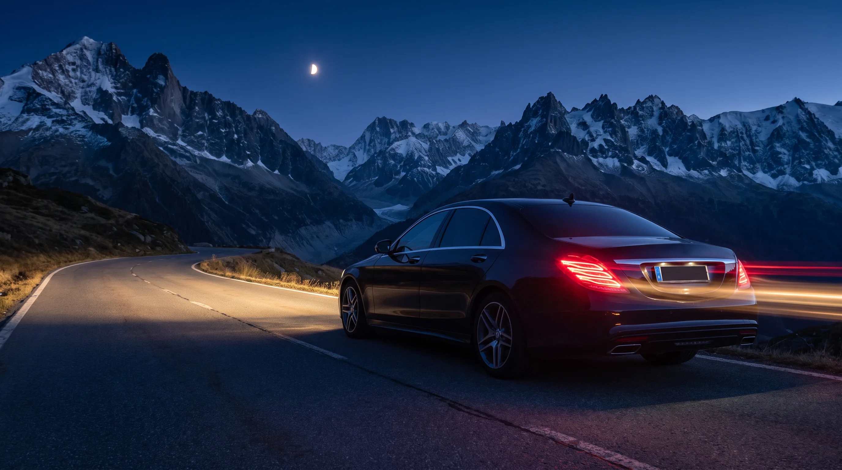 Inszenierte Szene: Limousine bei Nacht auf einer Alpenstraße, Bergsilhouetten im Mondlicht